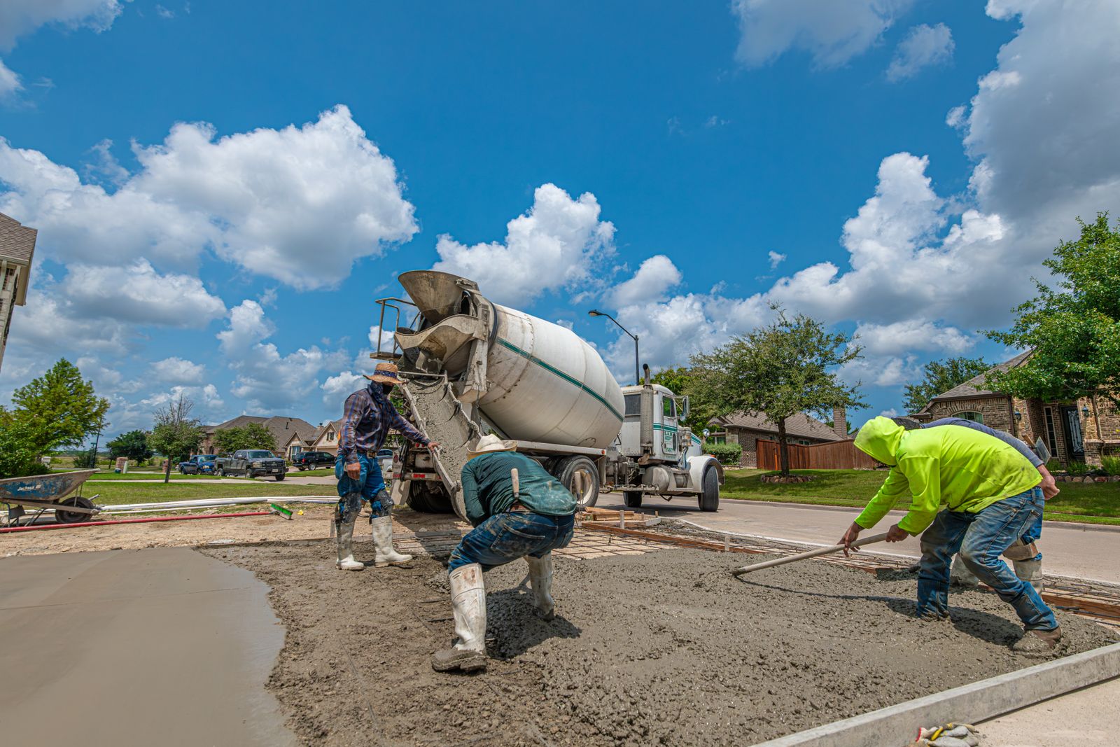 A Rolling Rock Concrete crew pouring and screeding a fresh residential concrete driveway from a mixer truck under a bright Southern Utah sky