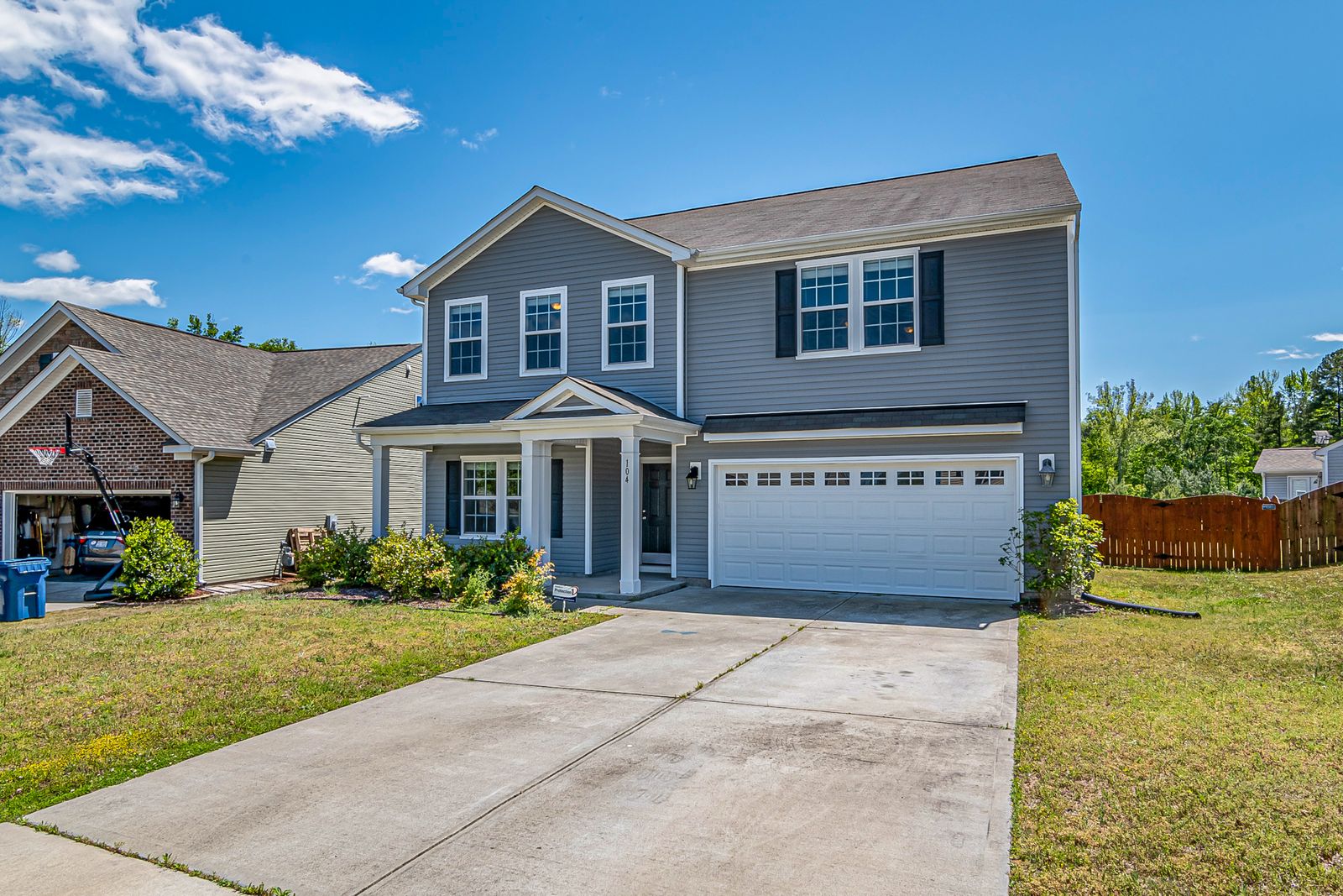 A finished home with a clean, broom-finished concrete driveway running to the garage